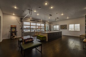 Ein geräumiges Zimmer mit großem Fenster, einer Küchenzeile, einer Bar und einem Billardtisch.