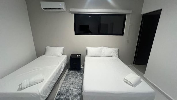 A twin room with two beds, a window, an air conditioner, and a small desk.
