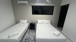 A twin room with two beds, a window, an air conditioner, and a small desk. - Departamentos 597 (Mérida)
