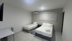 A bedroom with two beds, a desk, and an air conditioning unit.