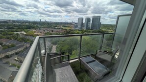 Ein Hochhaus mit Balkon, im Hintergrund eine Stadtansicht und ein klarer Himmel.