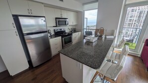 Eine moderne Küche mit Edelstahlgeräten, einer Granitabdeckung und Blick auf ein Hochhaus.