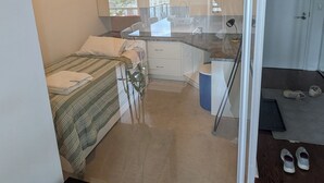 Eine moderne Wohnung mit Küchenzeile, Essbereich und Schlafzimmer mit Bett und kleinem Tisch.