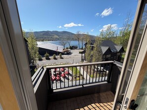 A balcony with a view of a lake, buildings, and a mountain in the distance.