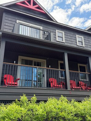 A two-story building with a balcony, red chairs, and a red logo on the roof.