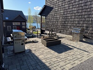 Un patio con una parrilla, asientos al aire libre y vista a un cuerpo de agua.