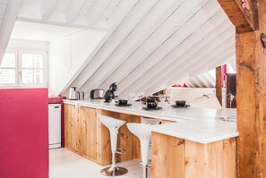 Eine moderne Küche mit weißer Arbeitsplatte, Holzschränken und zwei weißen Barhocker.