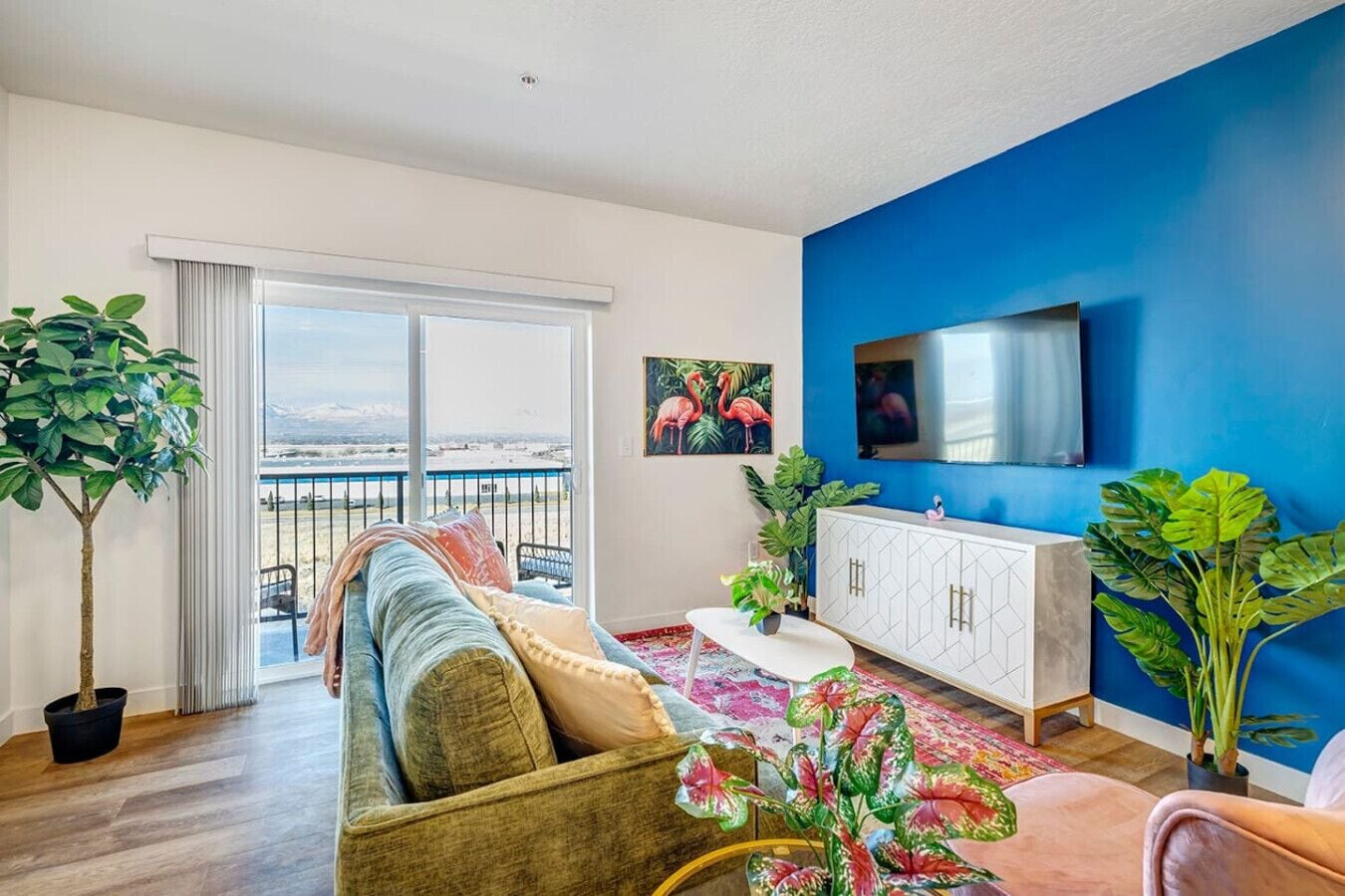 A modern living room with a sofa, a TV, a cabinet, and a balcony with a view.