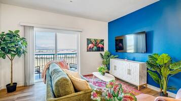A modern living room with a sofa, a TV, a cabinet, and a balcony with a view.