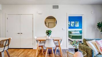 A compact living space with a dining area, a round mirror, a sofa, and a bed with a blue accent wall.
