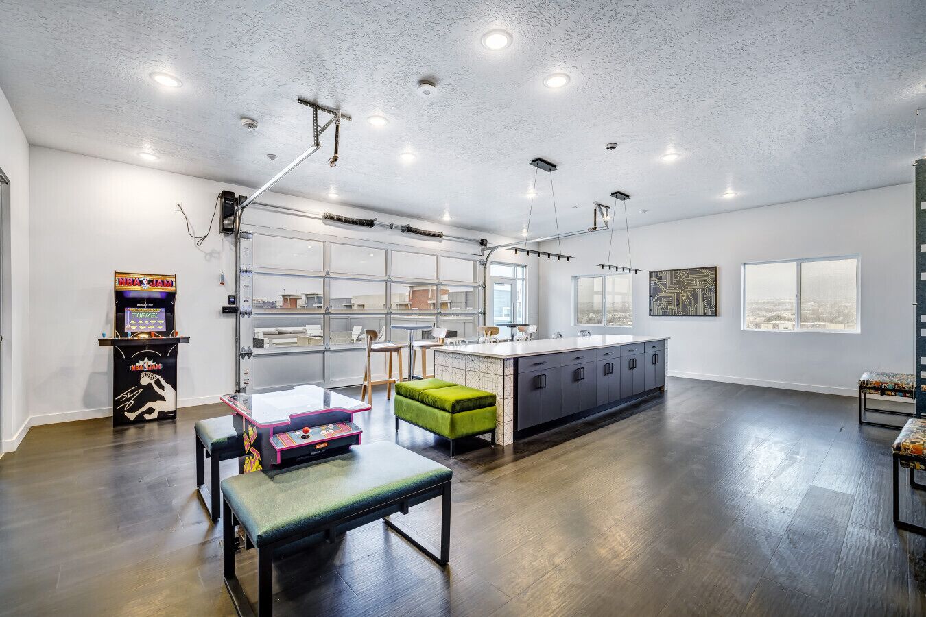 A spacious kitchen with a large island, modern lighting, and a view of the city.