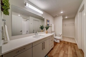 Ein modernes Badezimmer mit großem Spiegel, weißem Waschbecken und Toilette.