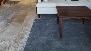 Quarto de sótão com um sofá branco, uma mesa de centro de madeira, uma mesa de jantar com cadeiras e uma porta de madeira.