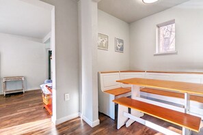 A room with a wooden bench seating area, a small table, and framed artwork on the wall. - The Fountain Creek Inn (Manitou Springs)