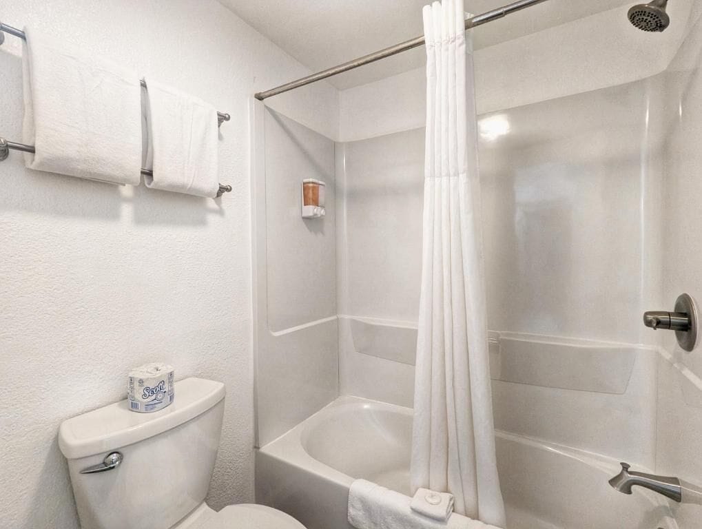 A bathroom with a toilet, a shower with a curtain, and a towel rack.