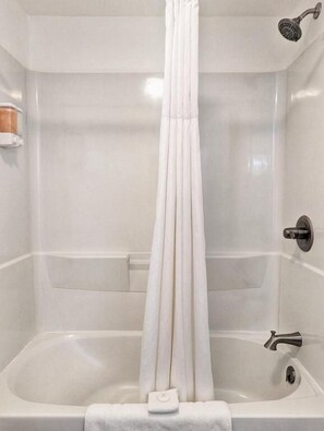 A bathroom with a bathtub, a showerhead, and a towel rack.