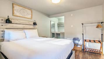 Un dormitorio con cama, cabecera de madera, lámpara colgante, armario y un tendedero.
