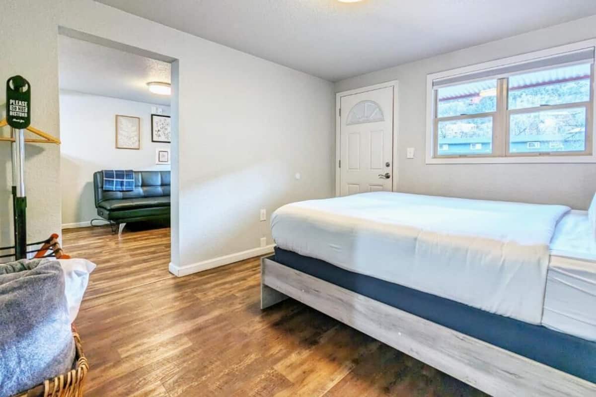 Un dormitorio con cama, ventana, puerta y una silla.