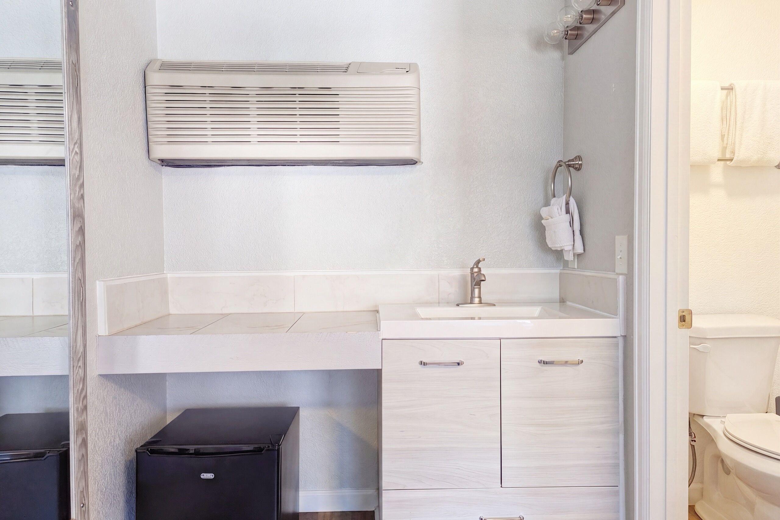 A bathroom with a white sink, a mirror, a towel rack, and a toilet.