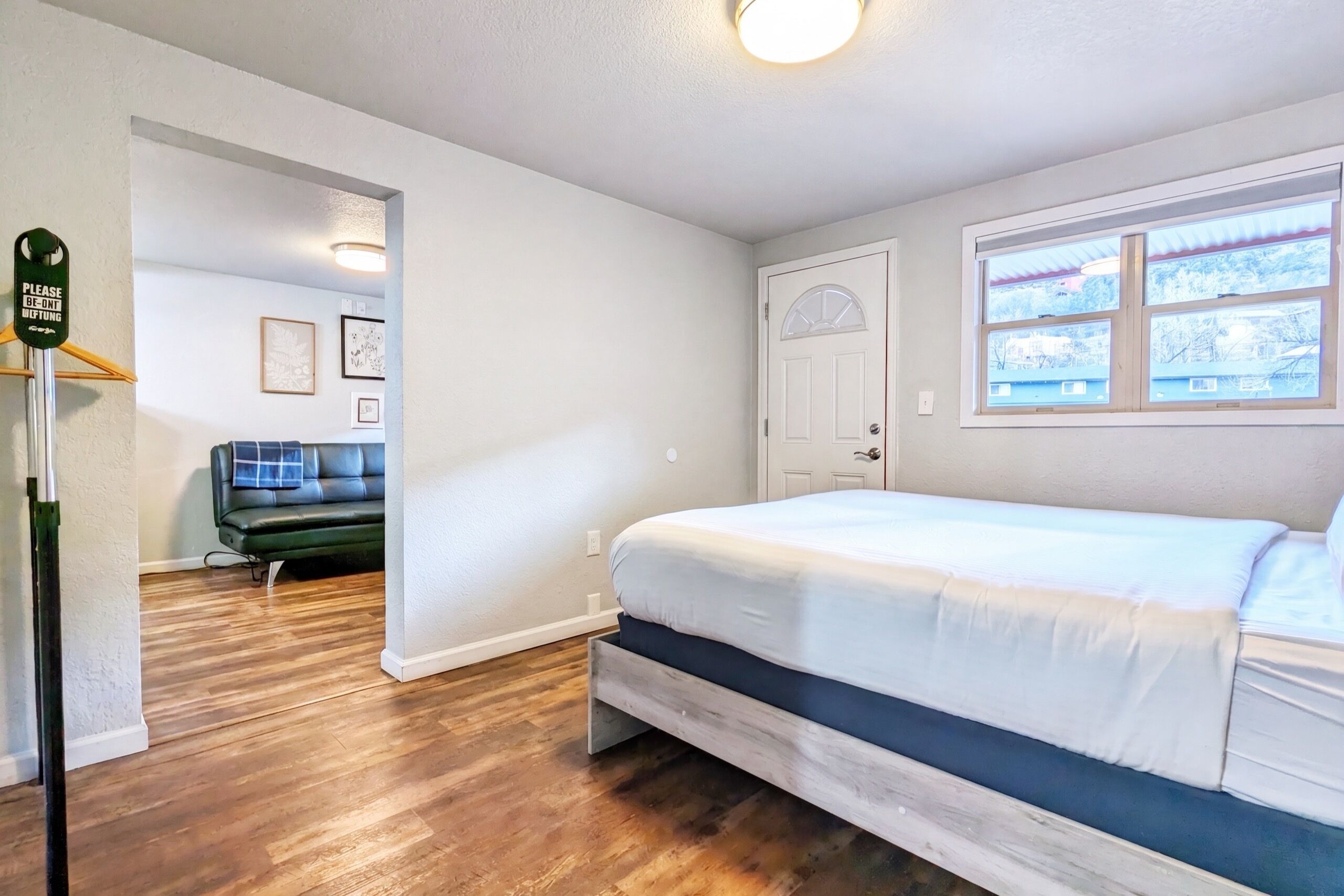Une chambre à coucher avec un lit, une porte, une fenêtre et un couloir menant à une autre pièce.