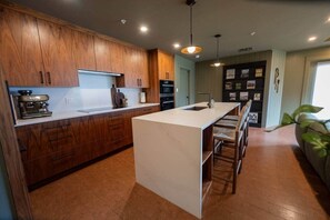 Een moderne keuken met houten kasten, een centraal eiland en een bar met zitplaatsen.