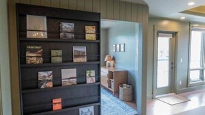 A hallway with a bookshelf, a wooden cabinet, and a door leading to another room. - Fernwood - Views ULTRA Comfort A+ Design 1335sf 4b (Canmore)