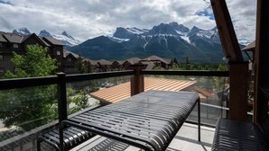 A balcony with a bench, overlooking a mountain range and a village. - Fernwood - Views ULTRA Comfort A+ Design 1335sf 4b (Canmore)