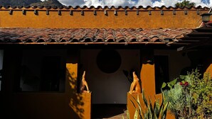A building with a tiled roof, a stone wall, and a statue of a figure. - Umbral (Tepoztlan)