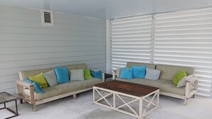 Una habitación con dos sofás de color claro, una mesa de centro de madera y una ventana con persianas.