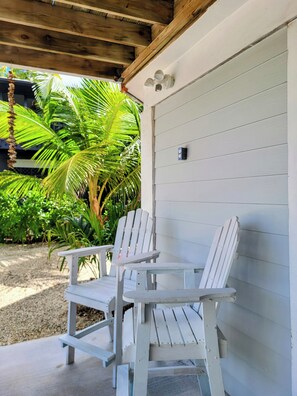 Eine überdachte Veranda mit zwei Adirondack-Stühlen, einer Holzbeschichtung und einer weißen Garagentür.
