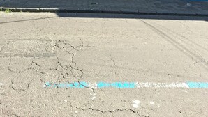 Un bâtiment avec une porte ou une fenêtre fermée, une rue devant, et une enseigne de pharmacie.