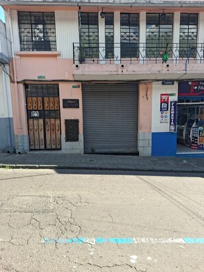 Ein Gebäude mit heruntergelassener Rollläde, eine Straße davor und ein Schild einer Apotheke.