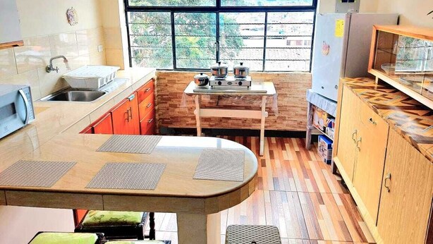Une cuisine avec une fenêtre, une cuisinière, un évier et une table avec des chaises.