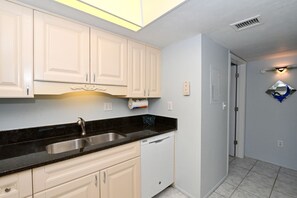 A kitchen with white cabinets, a black countertop, and a dishwasher.