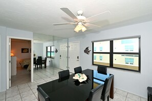 A conference room with a table, chairs, a ceiling fan, and a large window.