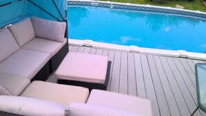 A poolside area with a white cushioned seating arrangement and a small table.