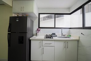 Eine Küche mit Kühlschrank, Schränken, einem Fenster und einer Spüle.