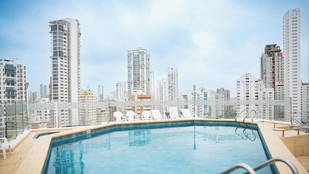 Piscina com espreguiçadeiras e vista para a cidade.
