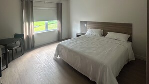 Habitación de hotel con una cama grande, un escritorio y una ventana con cortinas.