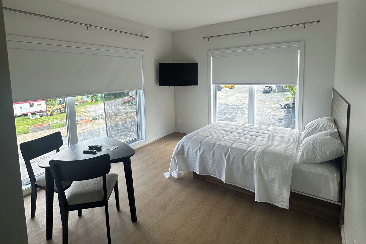 A bedroom with a bed, a TV, a table, and chairs.