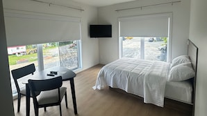 Un dormitorio con cama, televisor, mesa y sillas.