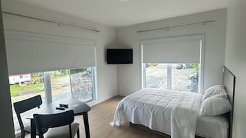 Un dormitorio con cama, televisor, mesa y sillas.