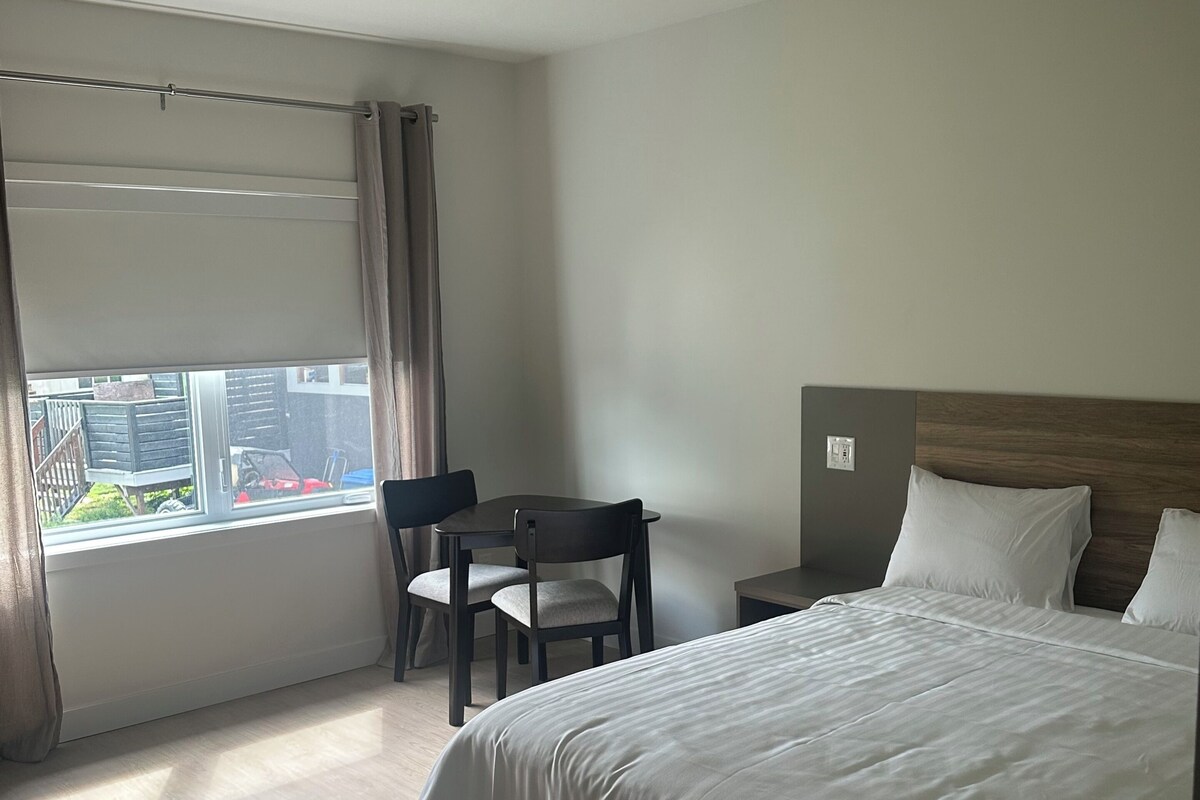 A hotel room with a bed, a desk, a chair, and a window with curtains.