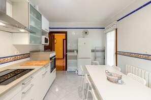 Eine moderne Küche mit weißen Schränken, einer Mikrowelle, einem Kühlschrank und einem Essbereich mit Tisch und Stühlen.