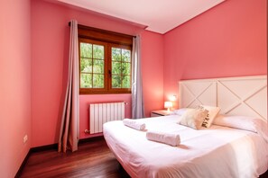 Una camera da letto con testiera in legno, una finestra con tende, un comodino con una lampada e un letto rifatto con asciugamani.