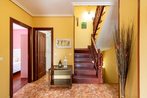 Ein Flur mit einer Holztreppe, einem Glastisch mit Dekoration und einer Tür zu einem Zimmer.