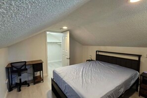 A bedroom with a bed, a desk, and a chair. - Cozy 2BR Retreat | King Bed | Private Deck | AC (Auburn)