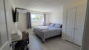 A bedroom with a bed, a desk, and a wardrobe. - Cozy 2BR Retreat | King Bed | Private Deck | AC (Auburn)