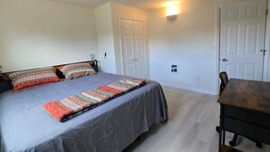 Un dormitorio con cama, una mesa y dos puertas.