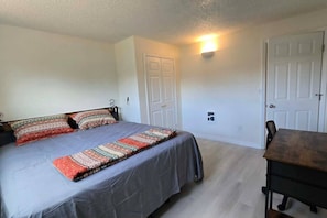 Un dormitorio con cama, una mesa y dos puertas.
